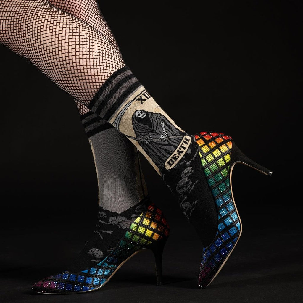 Death Tarot Card Crew Socks worn with fishnet stockings and rainbow high heels on a dark background.