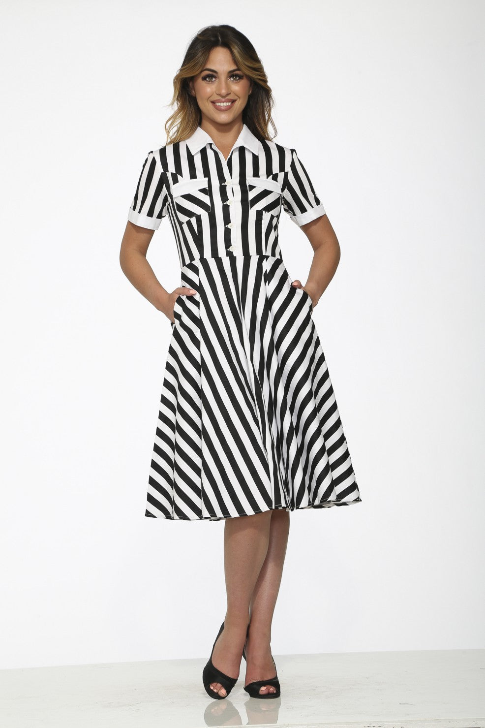 Model wearing a black and white striped swing dress with pockets and a collared neckline.