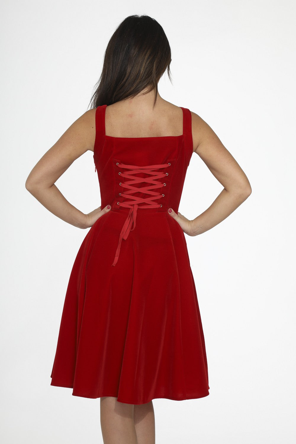 Red velvet swing dress with pockets showcasing the back lacing detail and full skirt design.