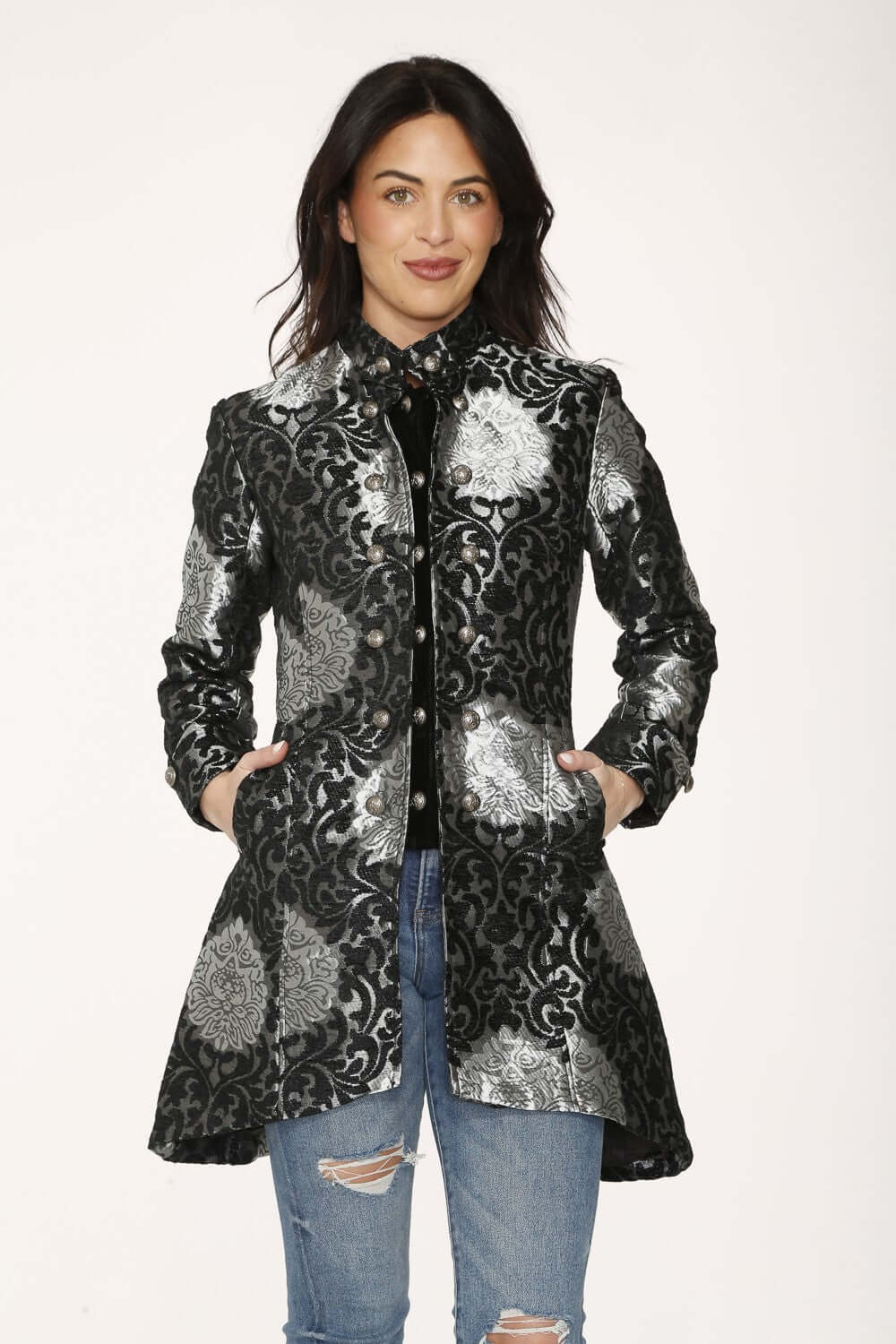 Elegant woman wearing a silver brocade women's coat with black detailing and tailored silhouette.