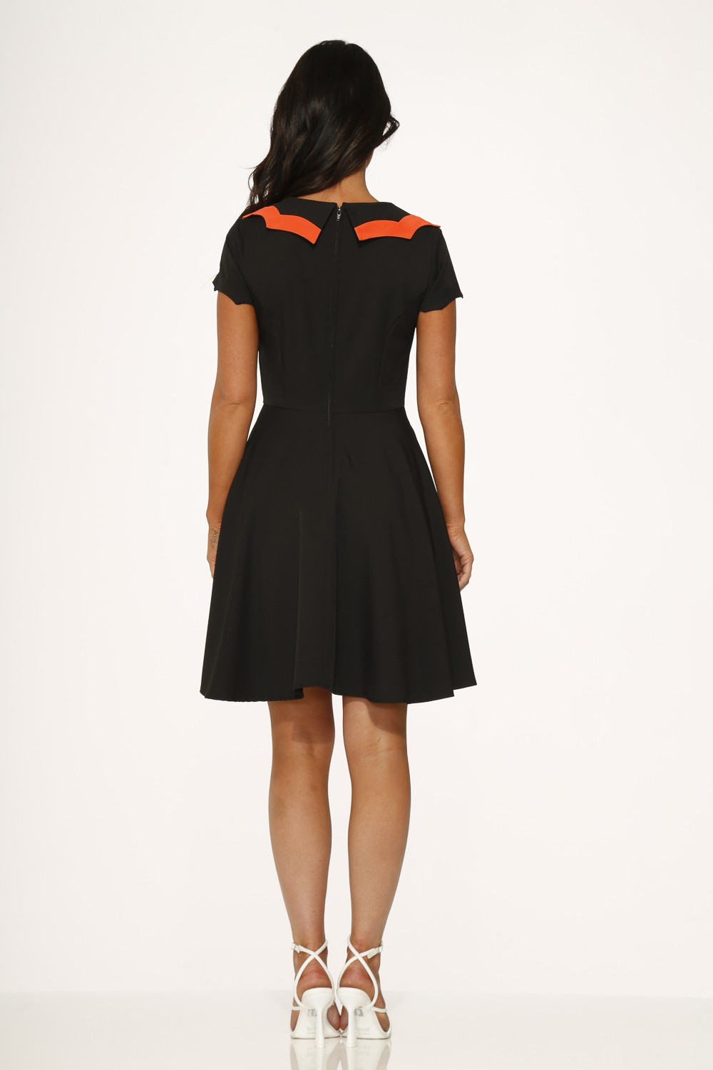 Back view of a black short sleeve swing dress with orange scalloped collar and flared skirt.