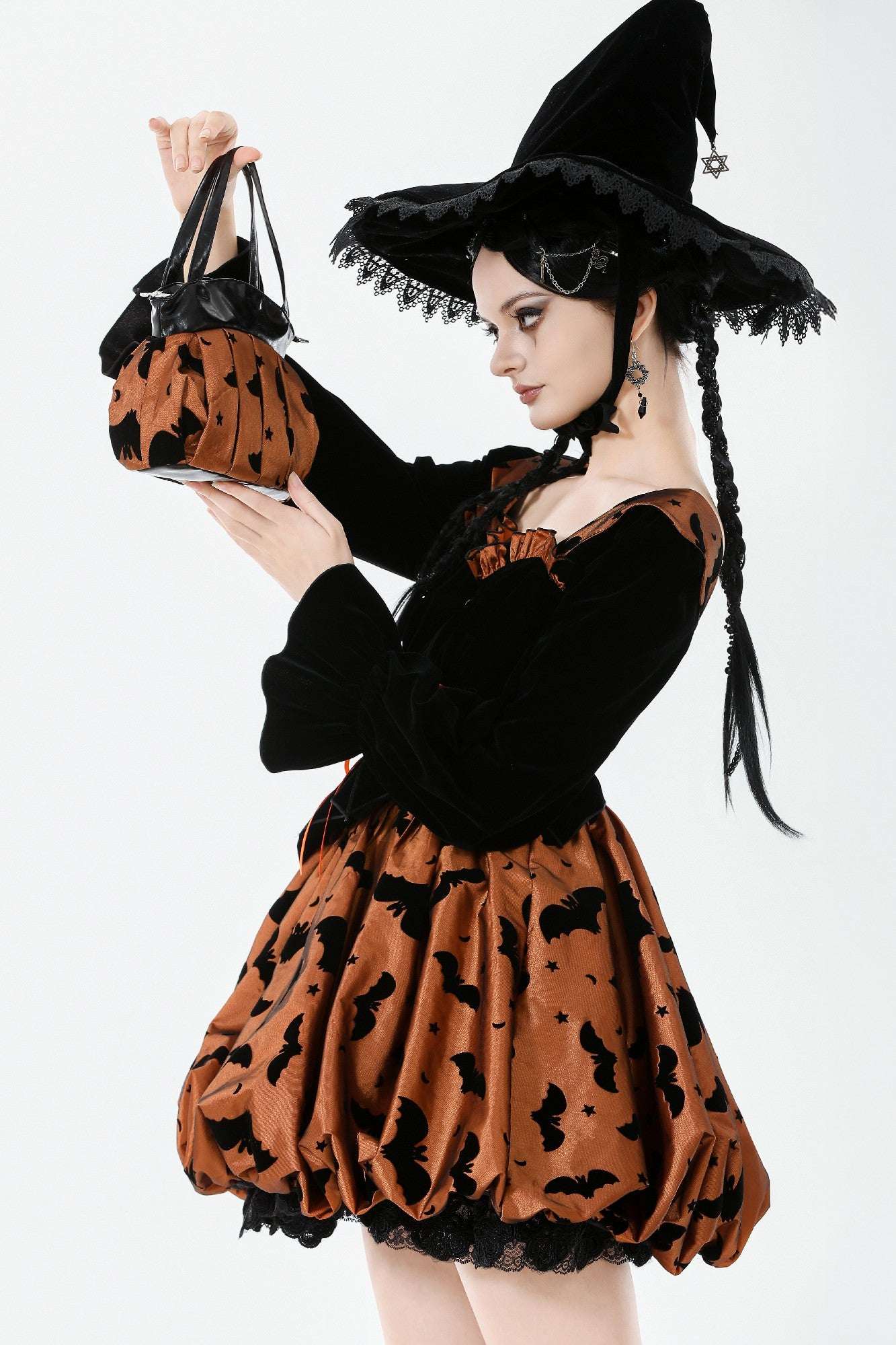 Woman in Halloween witch costume holding a matching handbag.