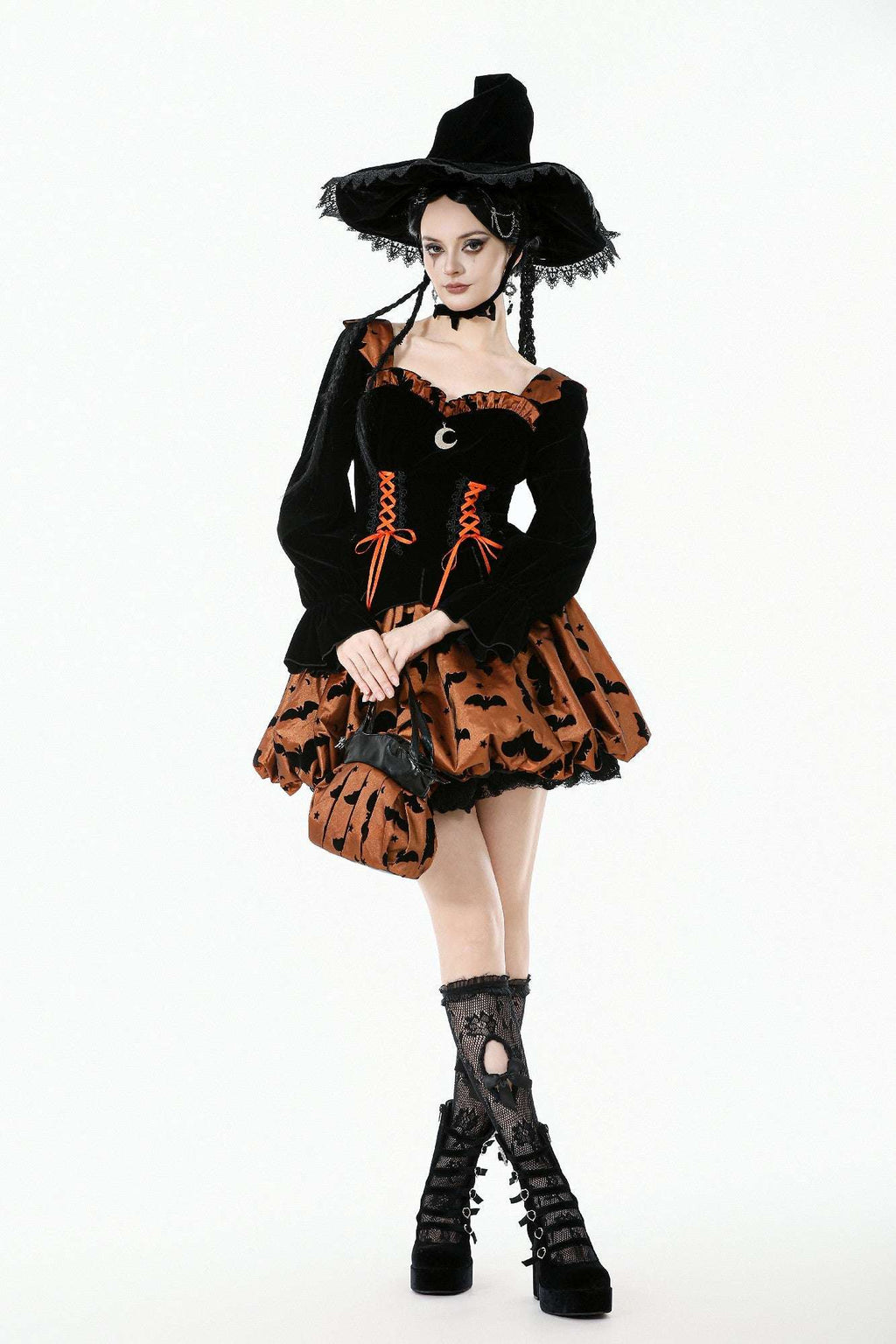 Person wearing a Halloween witch costume with black hat, dress, and boots on a white background