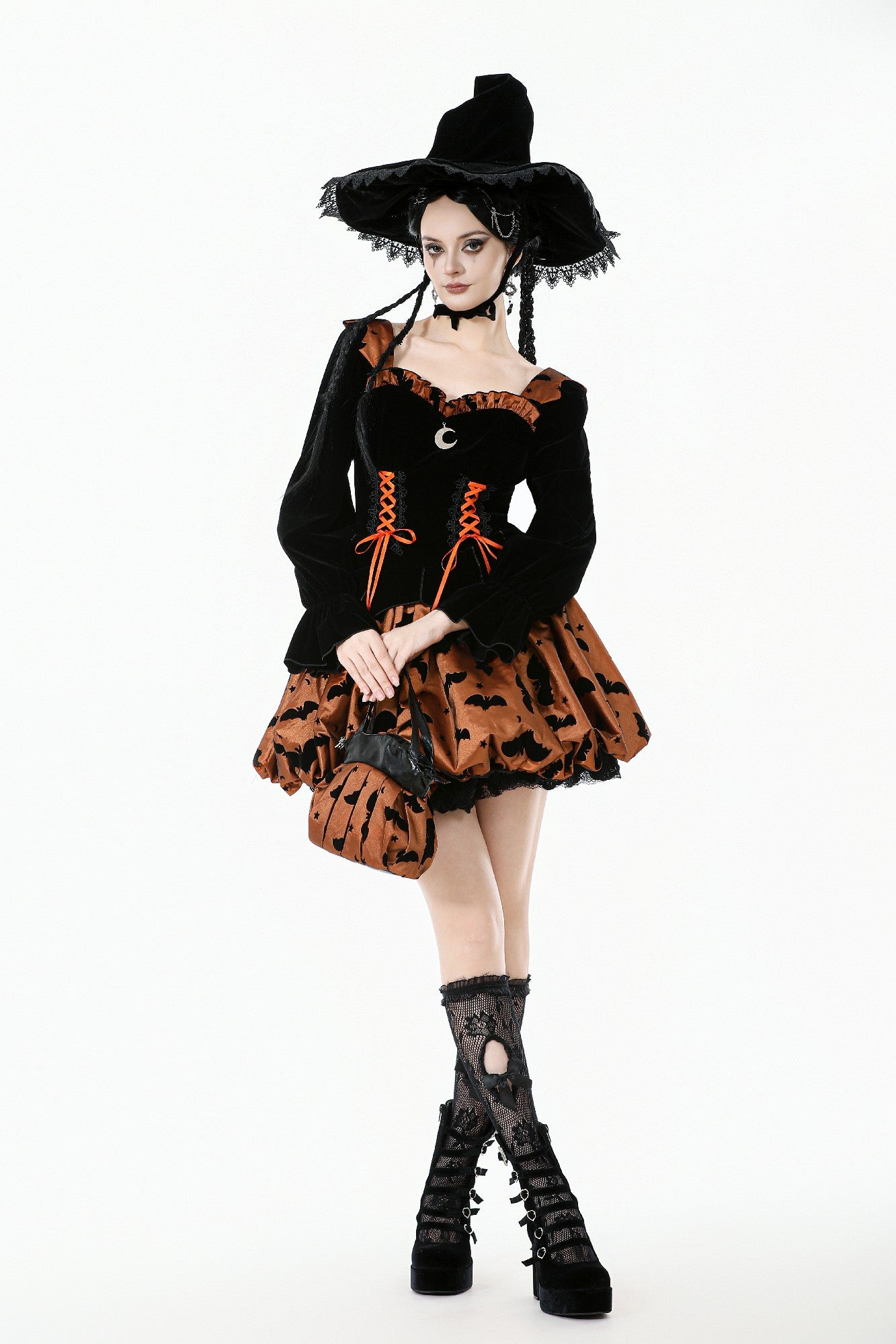Person wearing a Halloween witch costume with black hat, dress, and boots on a white background