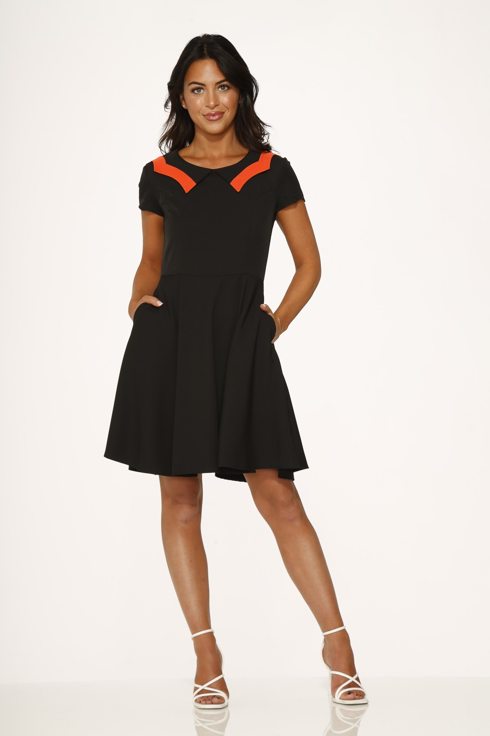 Black short sleeve swing dress with orange scalloped collar, featuring a flared skirt and hidden side pockets.