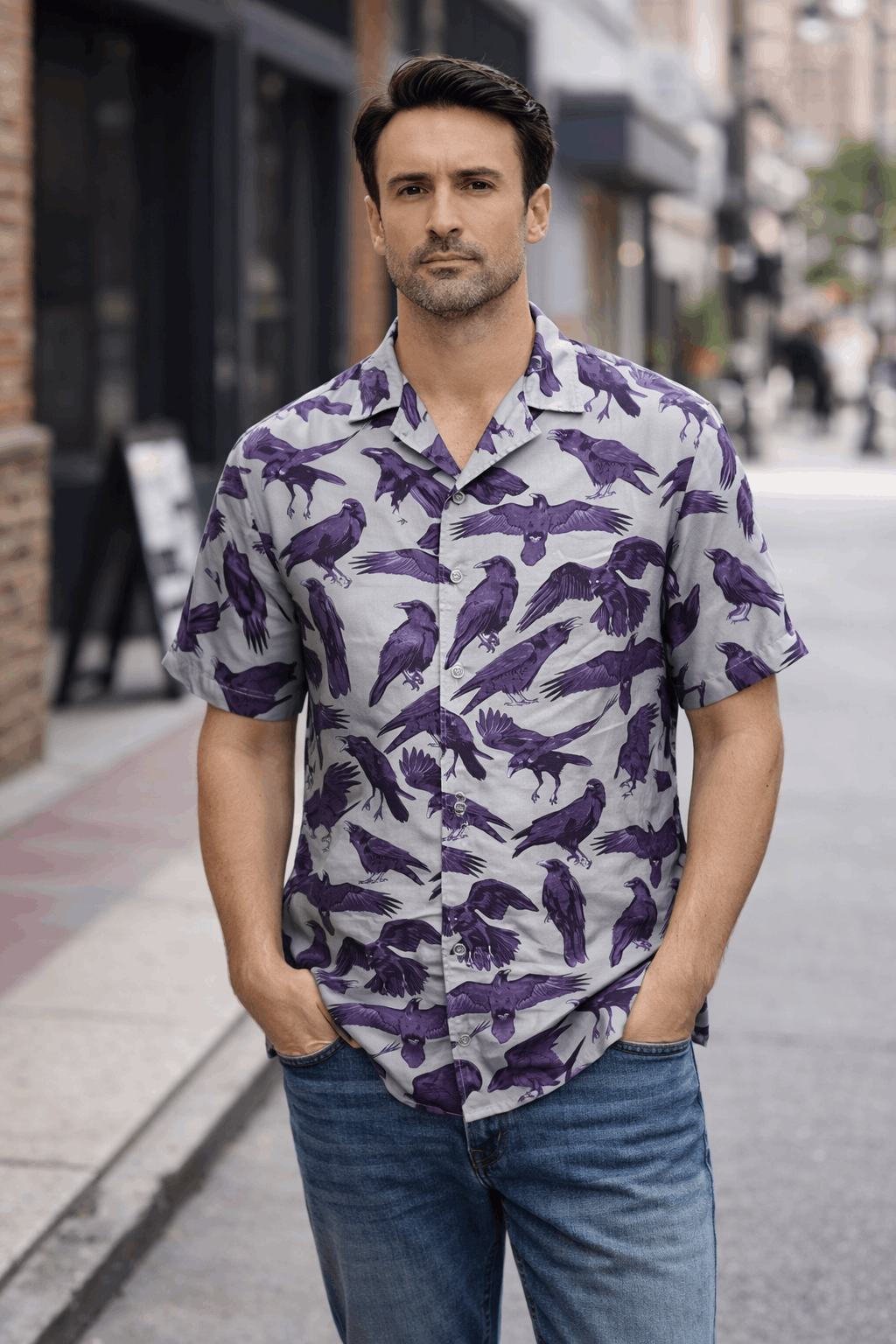 The Flock Gothic Button-Up Shirt worn by a man in a street, featuring purple-blue shadow ravens on a cool gray-green base.
