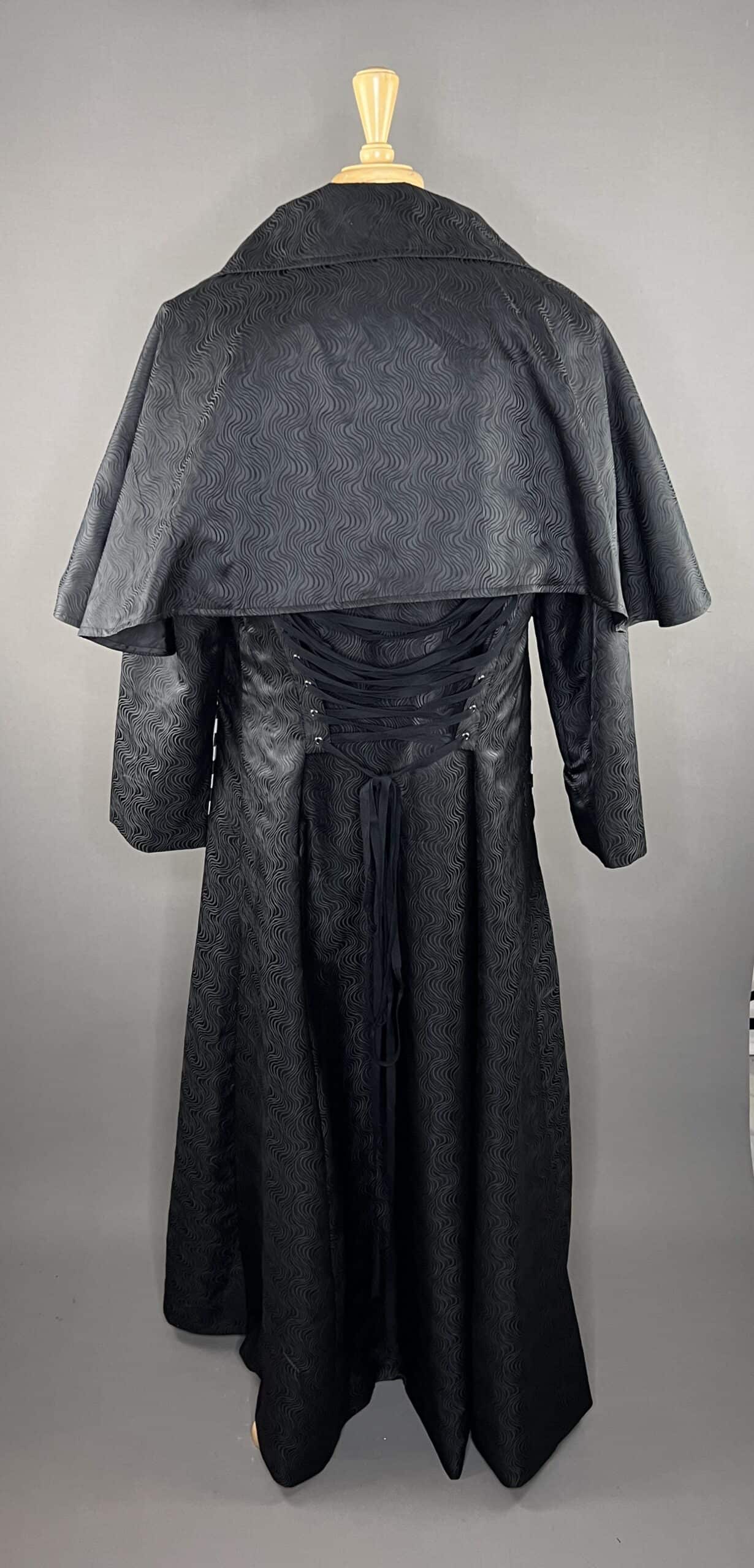 Swirling brocade cape coat showcasing dramatic cape-style silhouette and richly textured fabric.