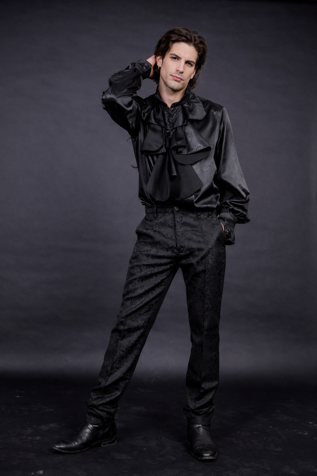 Black Gothic Trousers – Burleska Scroll Pattern Pants styled with a sleek dark shirt and black boots against a dark background.