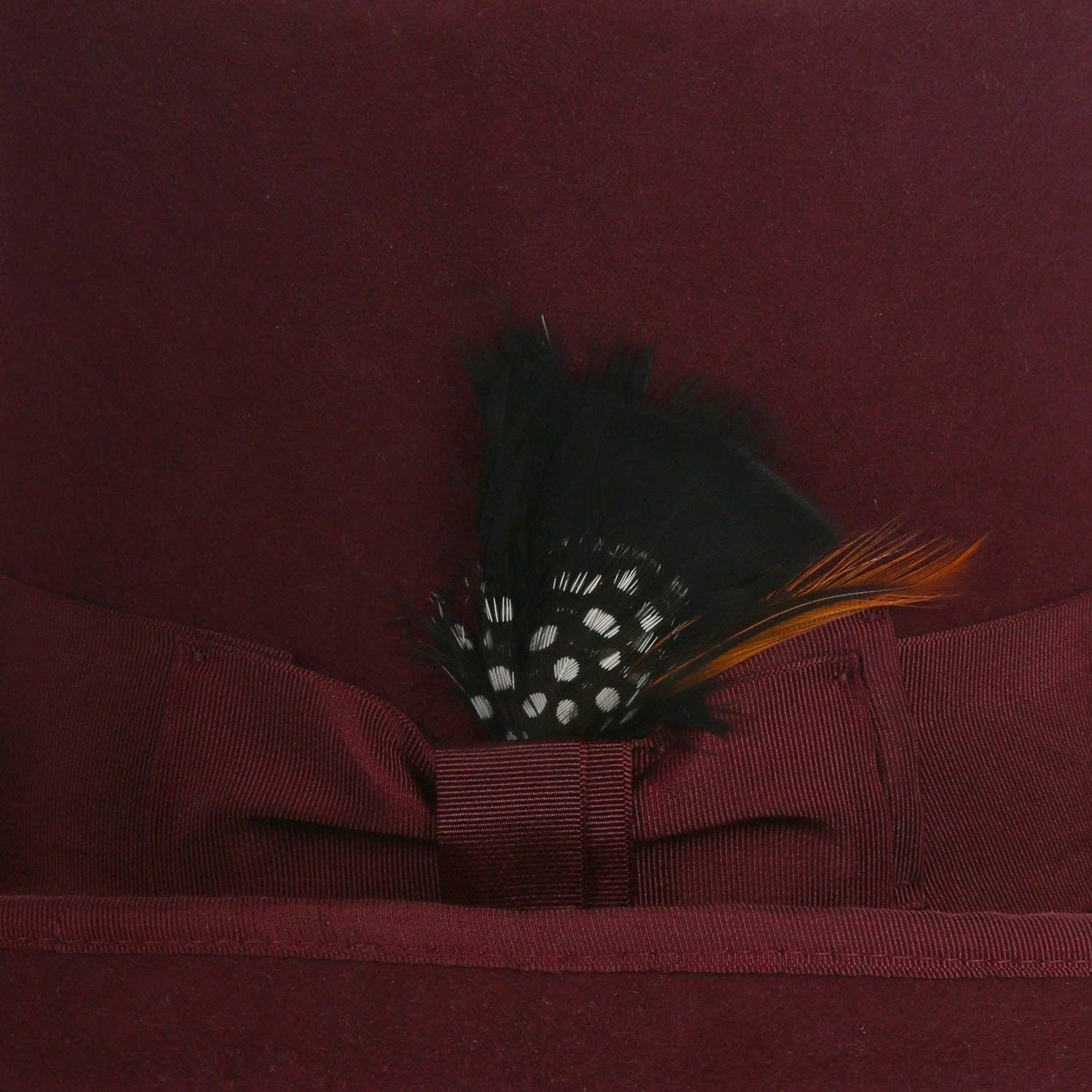  wool top hat in burgundy with grosgrain ribbon and feather accent.